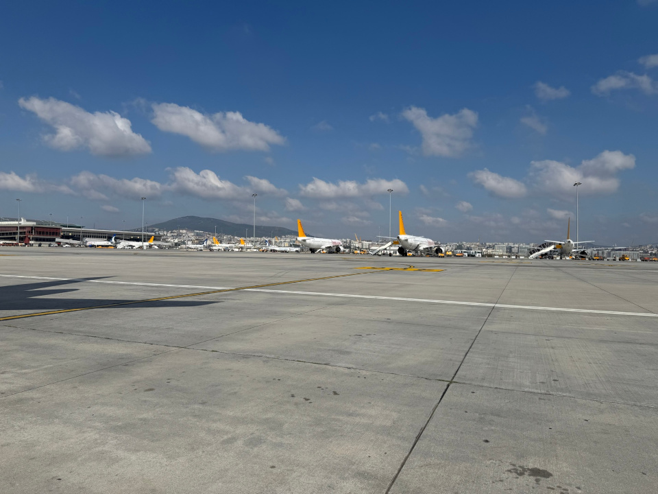 Wide view of Istanbul’s Sabiha Gökçen Airport tarmac with several Pegasus Airlines planes parked and low hills in the background.
